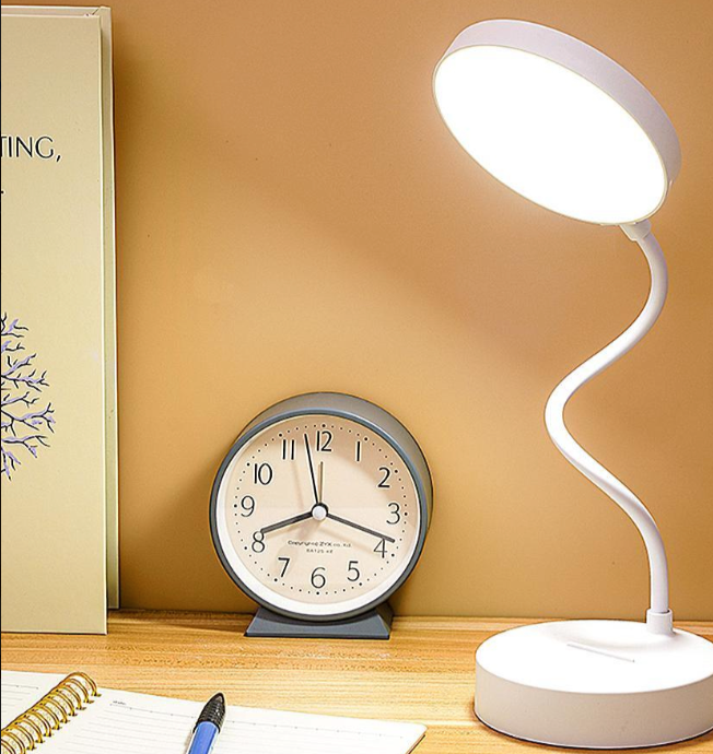 Desk lamp and clock on a wooden surface with a beige background