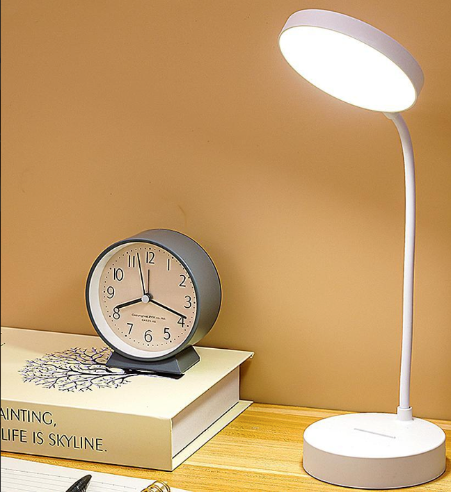 Desk lamp and clock on a book with a yellow background