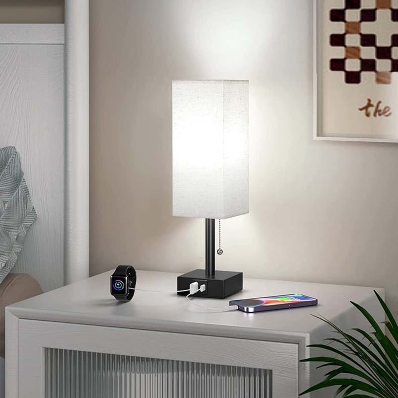 Lamp on a nightstand with a smartphone and smartwatch, in a room setting.