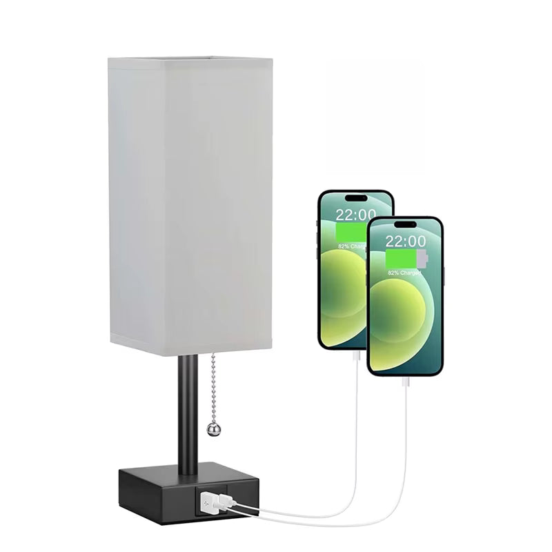 Table lamp with gray shade and black base, connected to two smartphones via a cable.