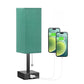 Green table lamp with a phone charging cable attached, on a white background
