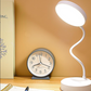 Desk lamp and clock on a wooden surface with a beige background