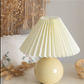 Yellow table lamp with pleated shade on a surface with decorative elements.